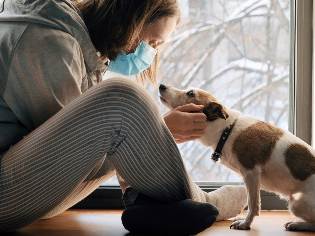 woman wearing a mask looking into her dog's eyes